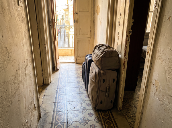 Stack of luggage by a front door in a Maltese apartment hallway