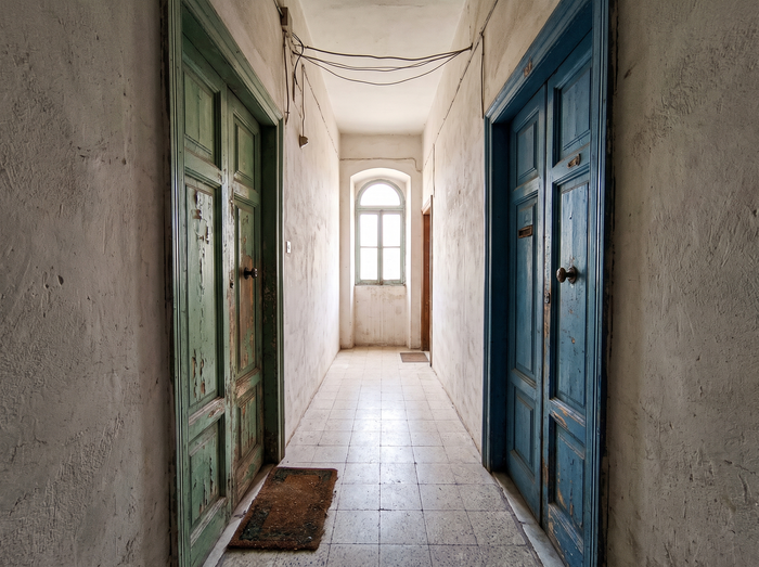 Two apartment front doors facing each other in a narrow Maltese hallway