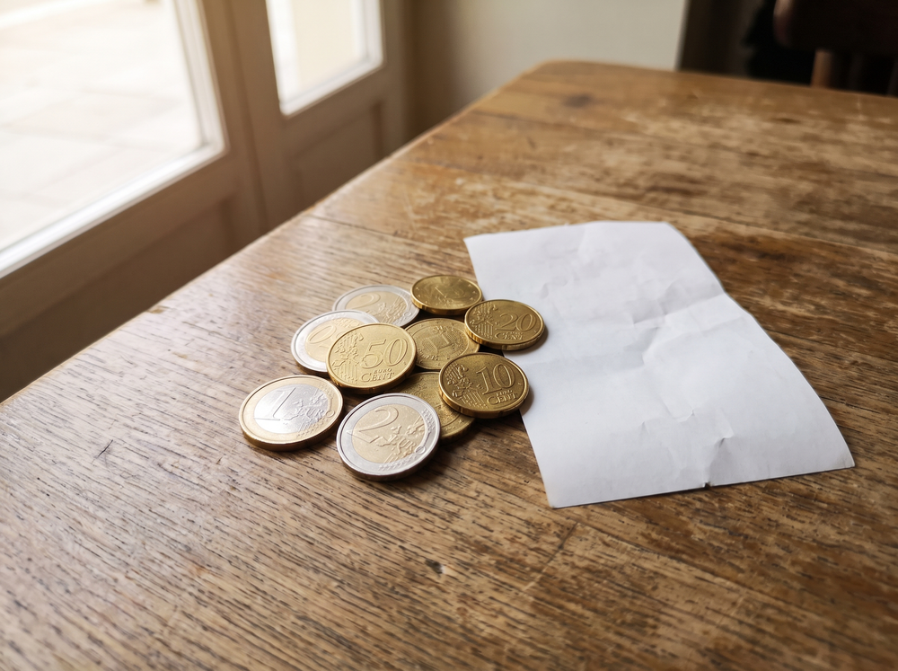 Coins and a small receipt on a wooden table